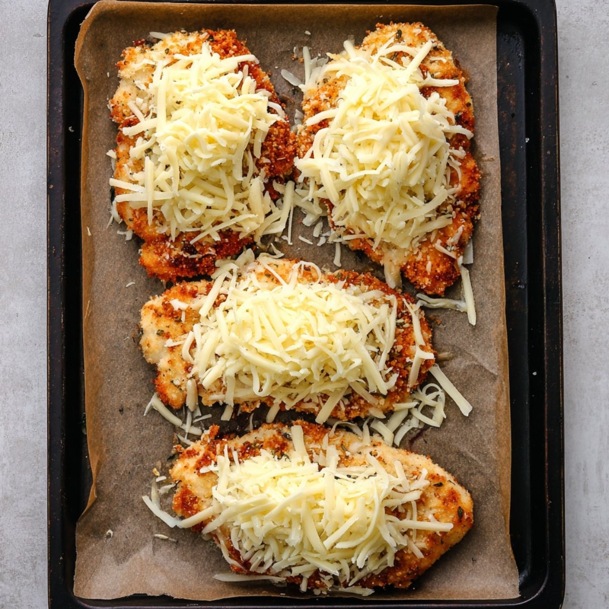 Place all four chicken cutlets on your prepared baking sheet. In a small bowl, mix together the mozzarella and Monterey Jack cheeses. Spoon a small mound of the cheese mixture onto each piece of chicken. Slide the pan into the oven and bake for 13 to 15 minutes, until the internal temperature hits 165°F and the cheese is melted and bubbly.